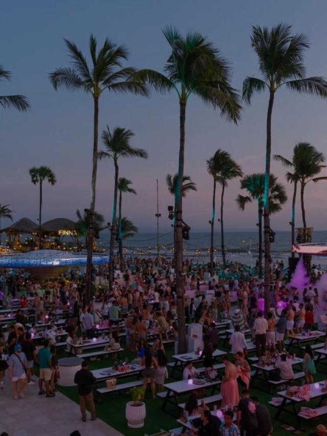 FINNS Beach Club at dusk, palm trees and ocean behind full tables